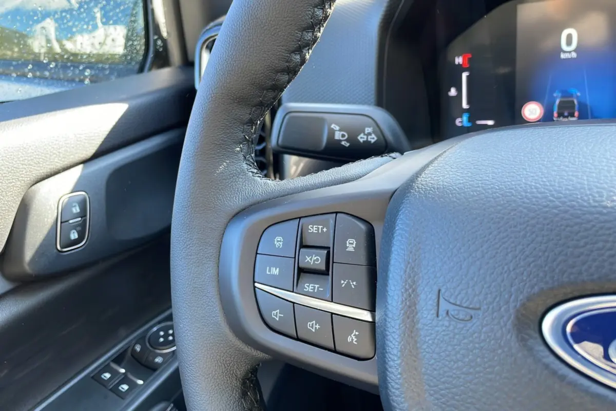 Gros plan sur le volant du Ford Ranger 2025 gris iconic, montrant les commandes de régulateur et l'affichage numérique au tableau de bord.