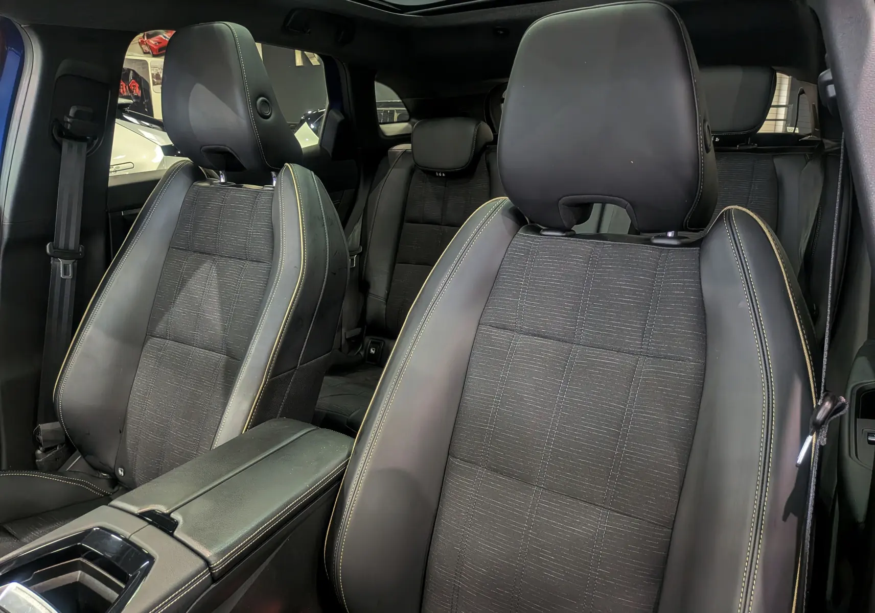 Intérieur du Renault Austral E-Tech Hybrid 2024, vue rapprochée des sièges avant en cuir noir avec surpiqûres jaunes.