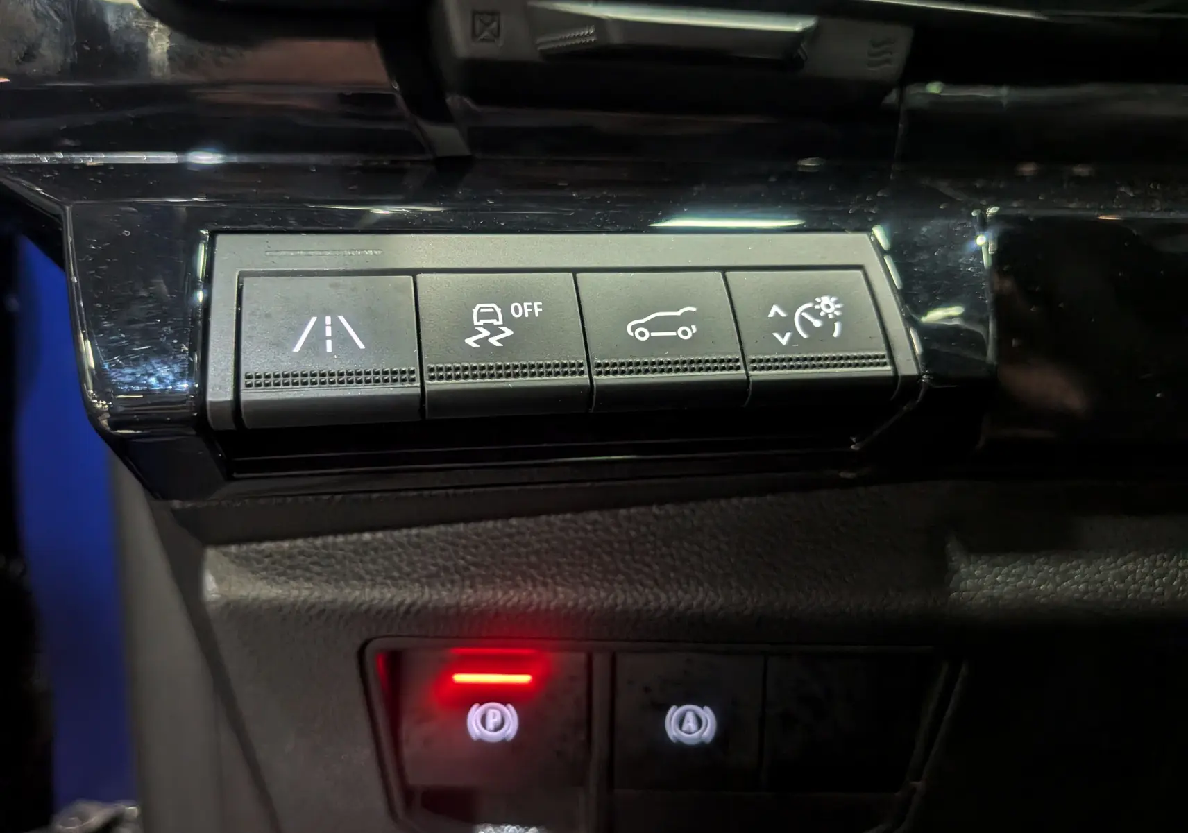 Panneau de commandes avec boutons d'assistance et frein à main électronique allumé dans un Renault Austral E-Tech Hybrid 2024.
