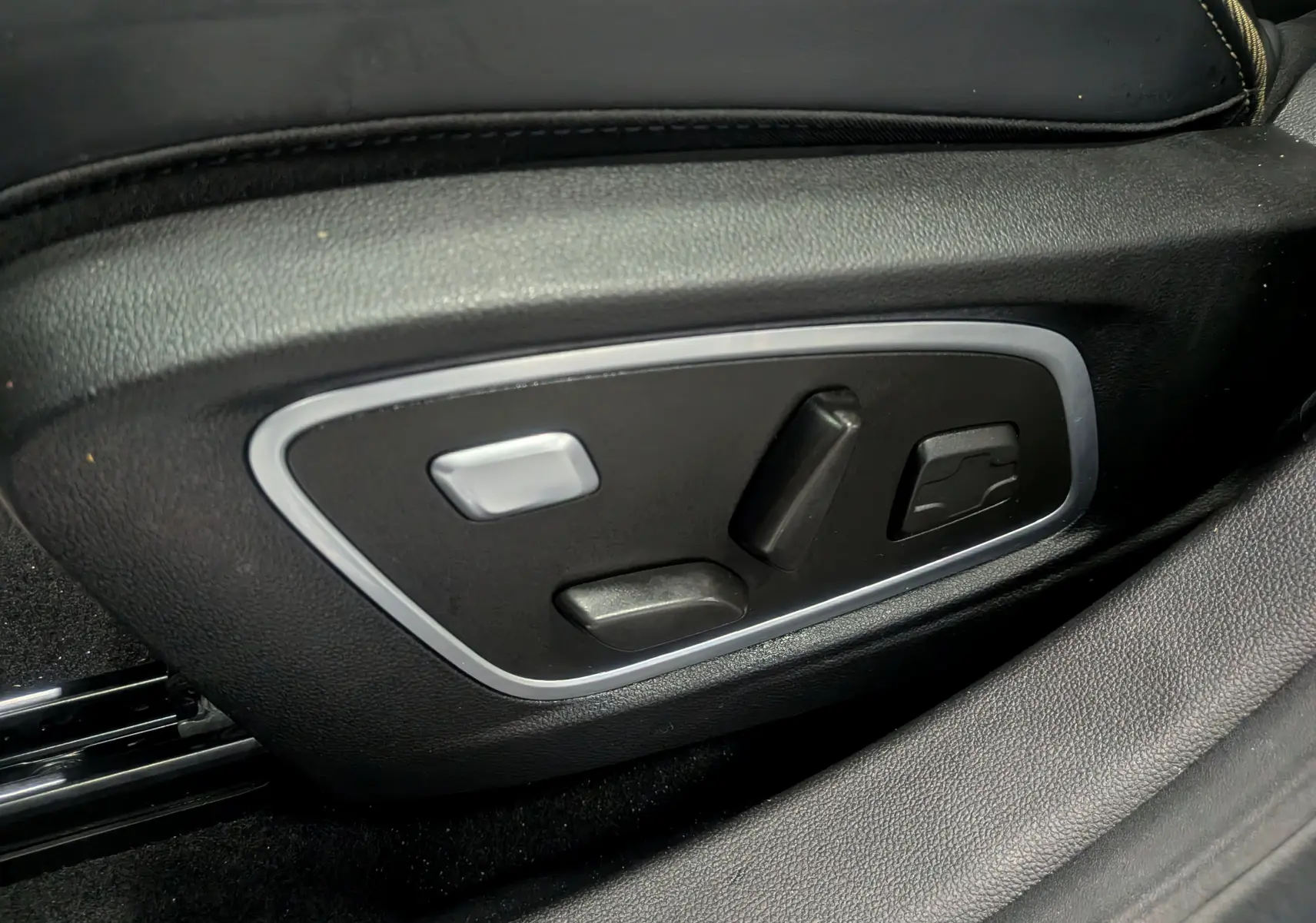 Gros plan sur les commandes électriques du siège conducteur en cuir noir du Renault Austral E-Tech Hybrid 2024.