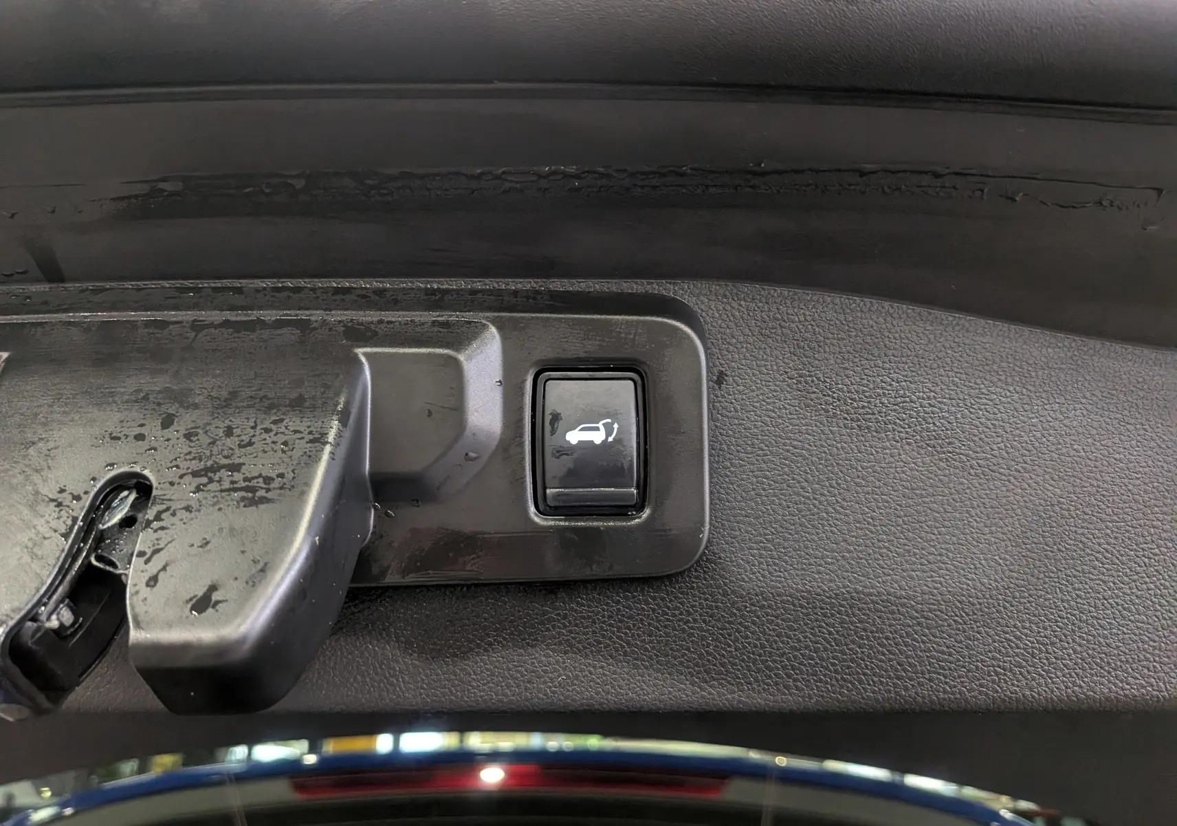 Bouton d'ouverture électrique du coffre sur la garniture intérieure d'un Renault Austral Bleu Iron 2024.