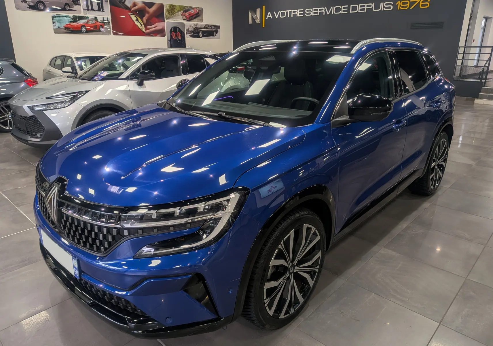 Renault Austral E-Tech Hybrid 200 ch Iconic bleu Iron en 3/4 avant droit, avec jantes alliage et calandre distinctive.