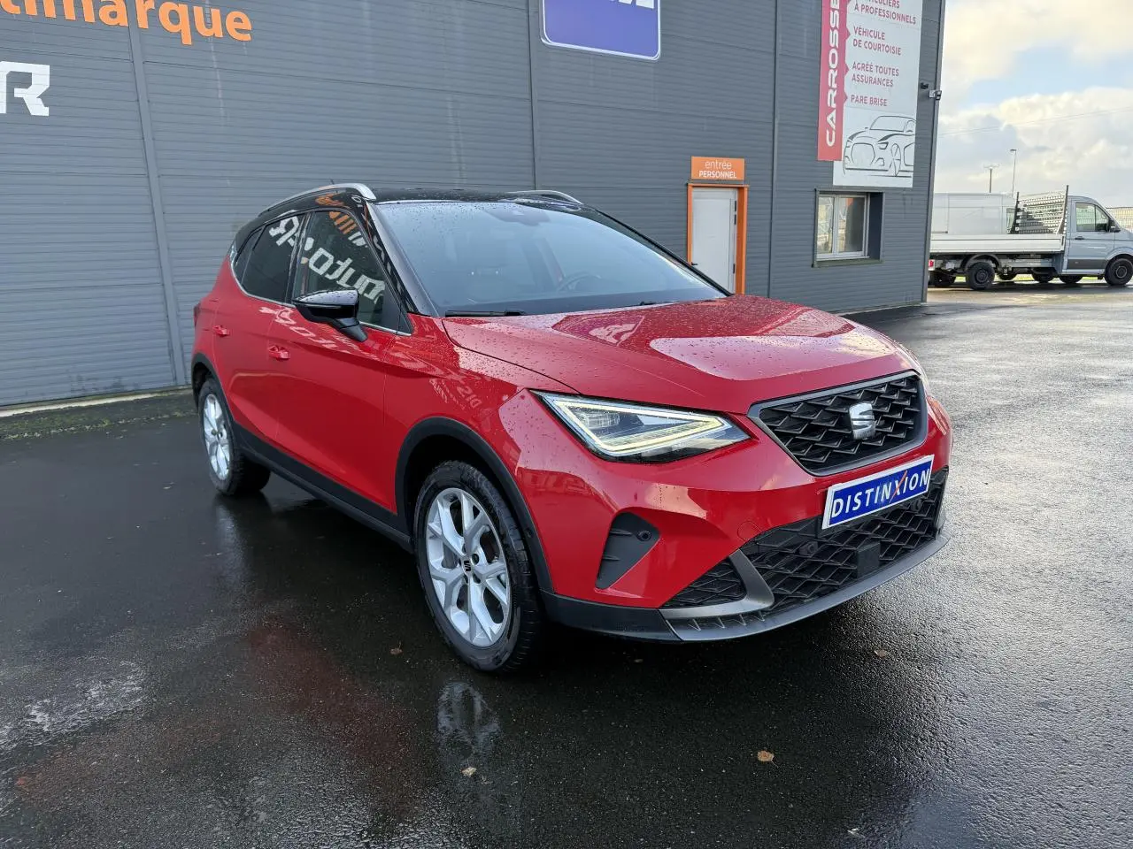 SEAT Arona rouge pur vue 3/4 avant droit, avec projecteurs LED et calandre noire distinctive.
