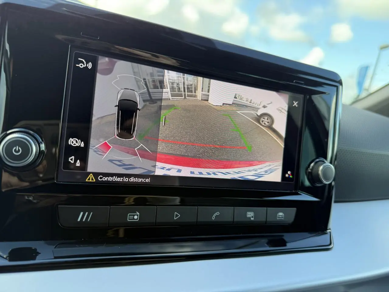 Écran central du SEAT Arona 2024 montrant la caméra de recul et l'assistance au stationnement en extérieur.