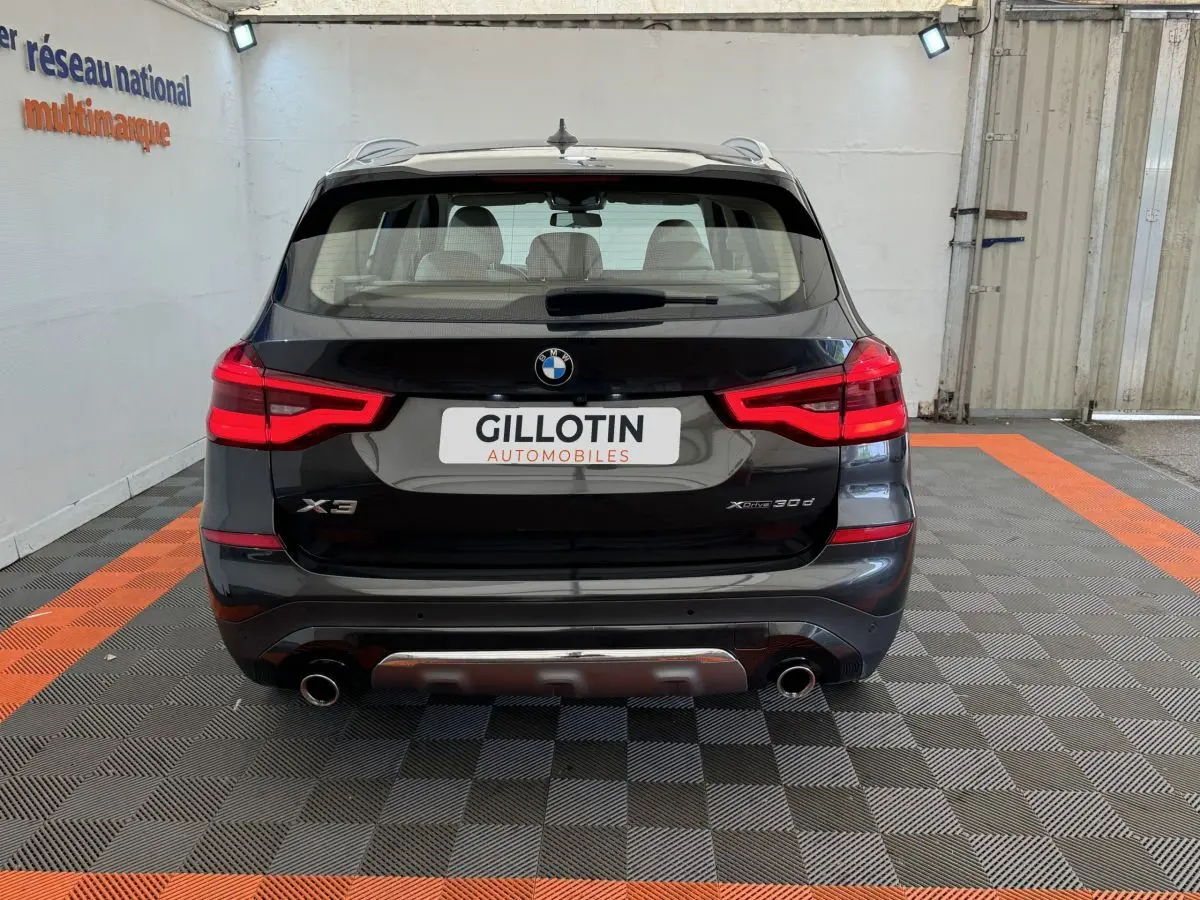 Vue arrière d’un BMW X3 xDrive30d gris foncé avec feux LED et double sortie d’échappement chromée.