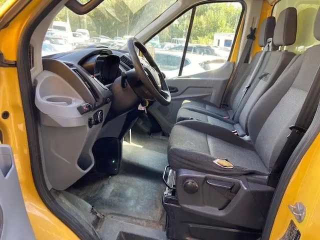 Intérieur côté conducteur du Ford Transit Chassis Cabine jaune, montrant tableau de bord et sièges gris en tissu.
