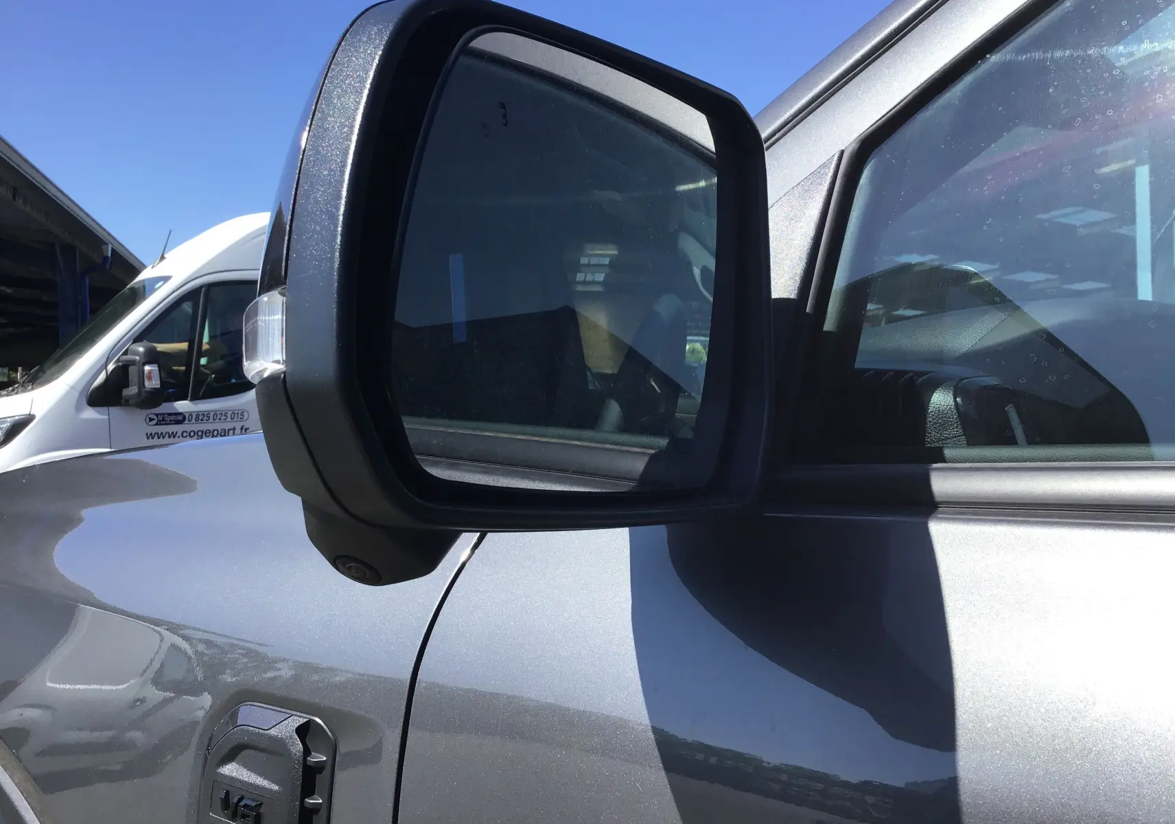 Rétroviseur côté gauche en gros plan du Ford Ranger Double Cabine gris carbone 2025 avec détails de la portière et vitre.