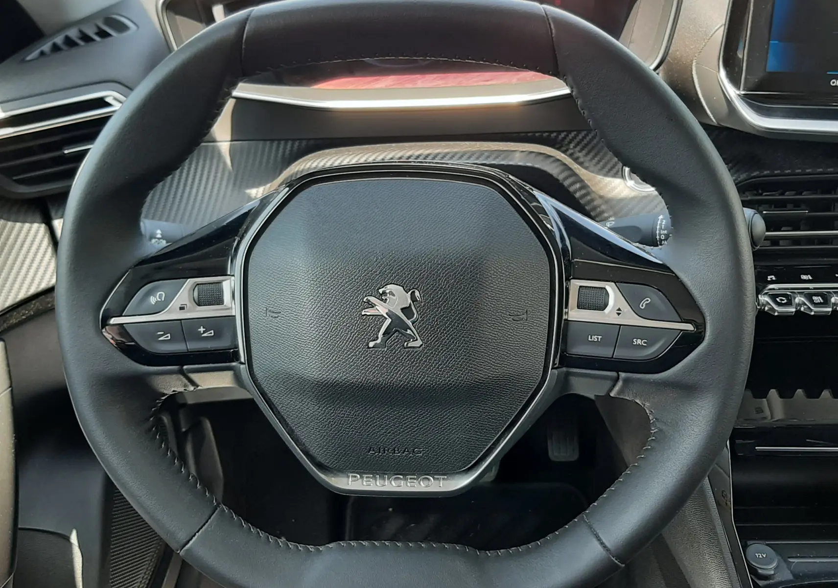 Volant noir de Peugeot 2008 2022 vue de face, avec commandes intégrées et tableau de bord partiellement visible.