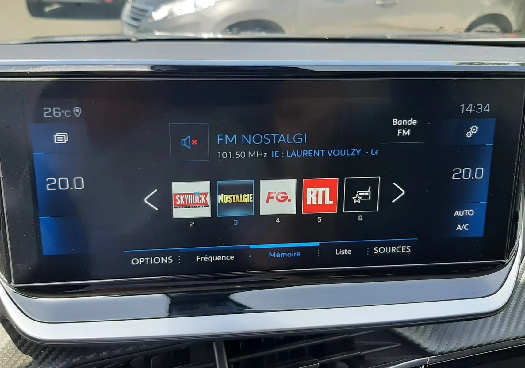 Écran tactile central du Peugeot 2008 gris Artense affichant les stations radio FM avec commandes climatisation à 20°C.