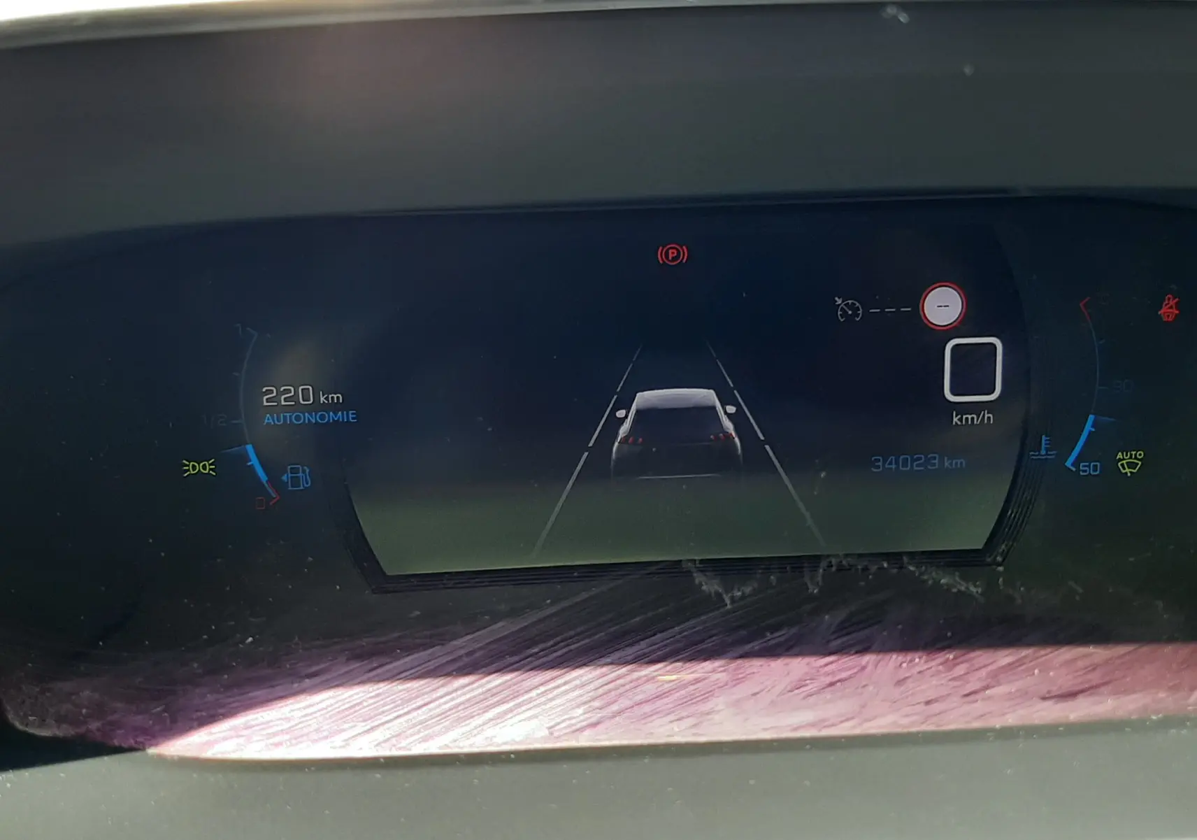 Affichage numérique du tableau de bord du Peugeot 2008 gris Artense montrant l'autonomie et l'assistance à la conduite