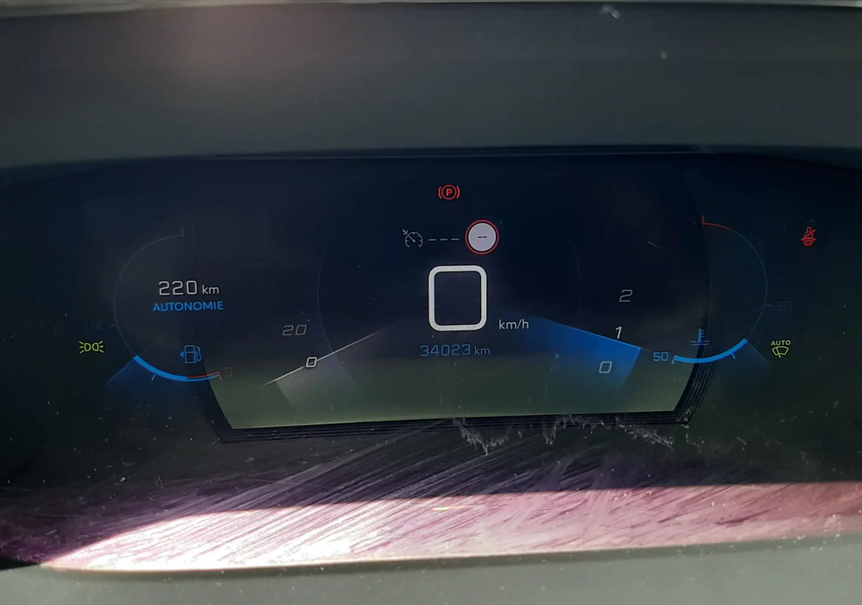 Tableau de bord numérique du Peugeot 2008 gris Artense, affichant 220 km d'autonomie et 34 023 km au compteur.