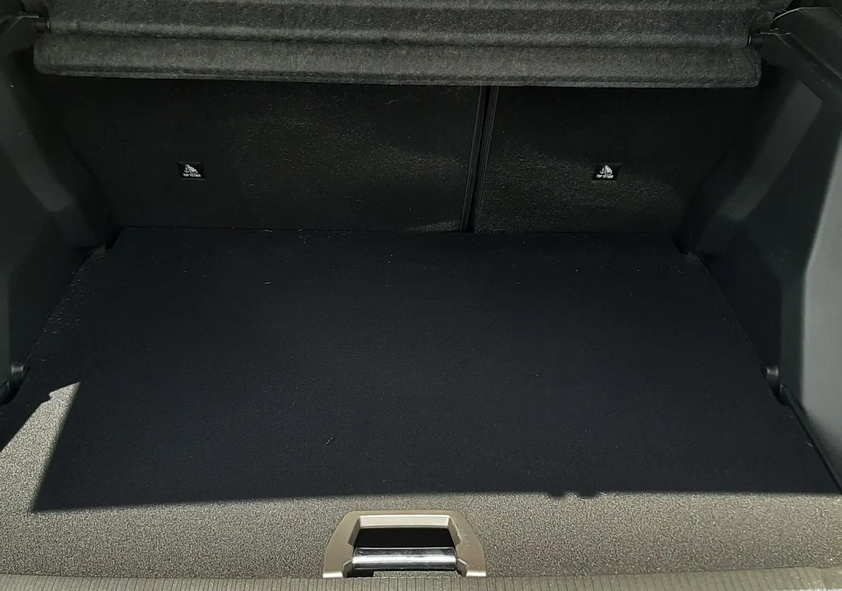Coffre ouvert du Peugeot 2008 gris Artense, vue intérieure montrant l'espace de chargement vide et la moquette noire.