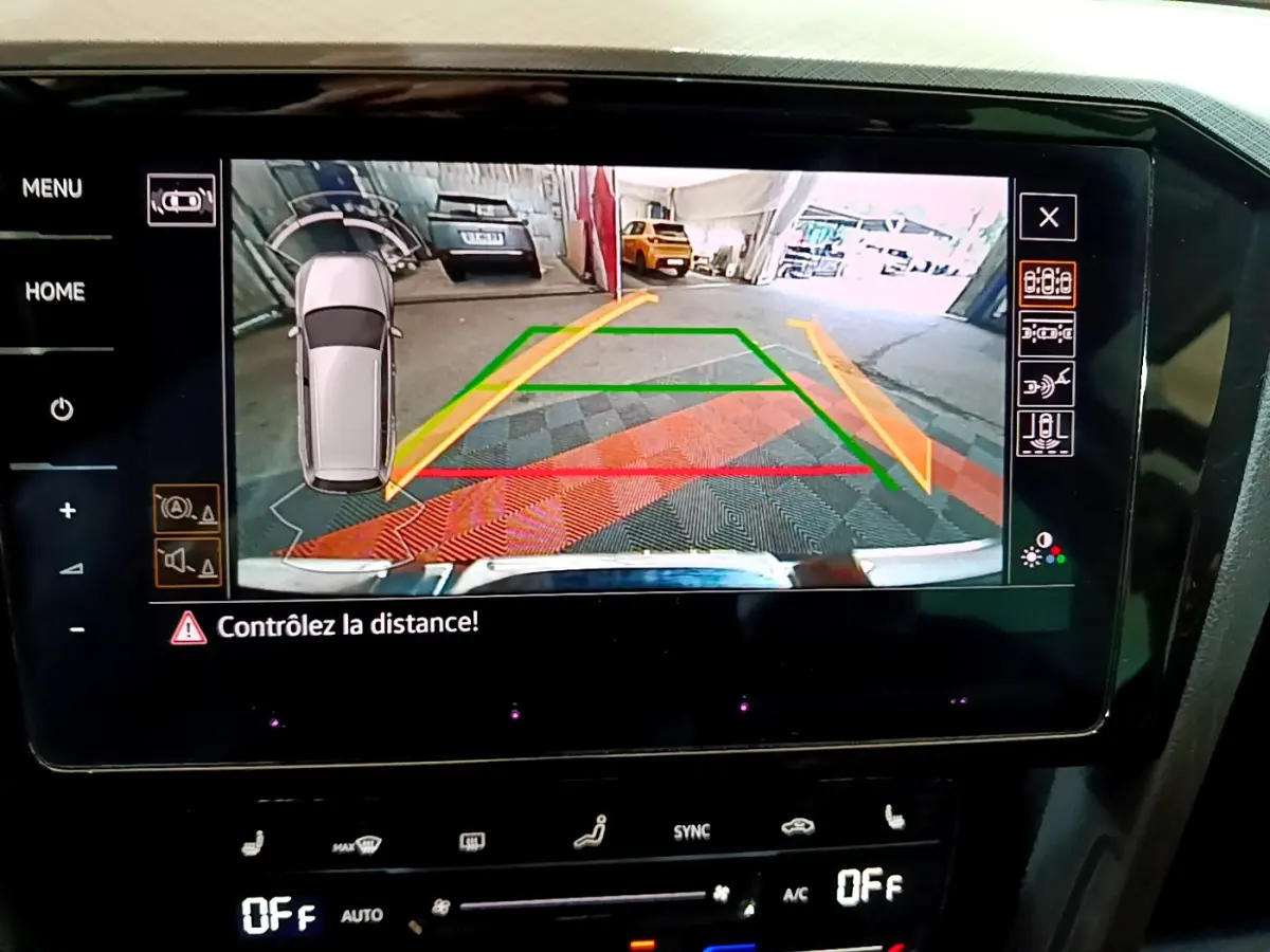 Écran tactile intérieur montrant la caméra de recul avec guidage dynamique d'une Volkswagen Passat gris foncé en stationnement.