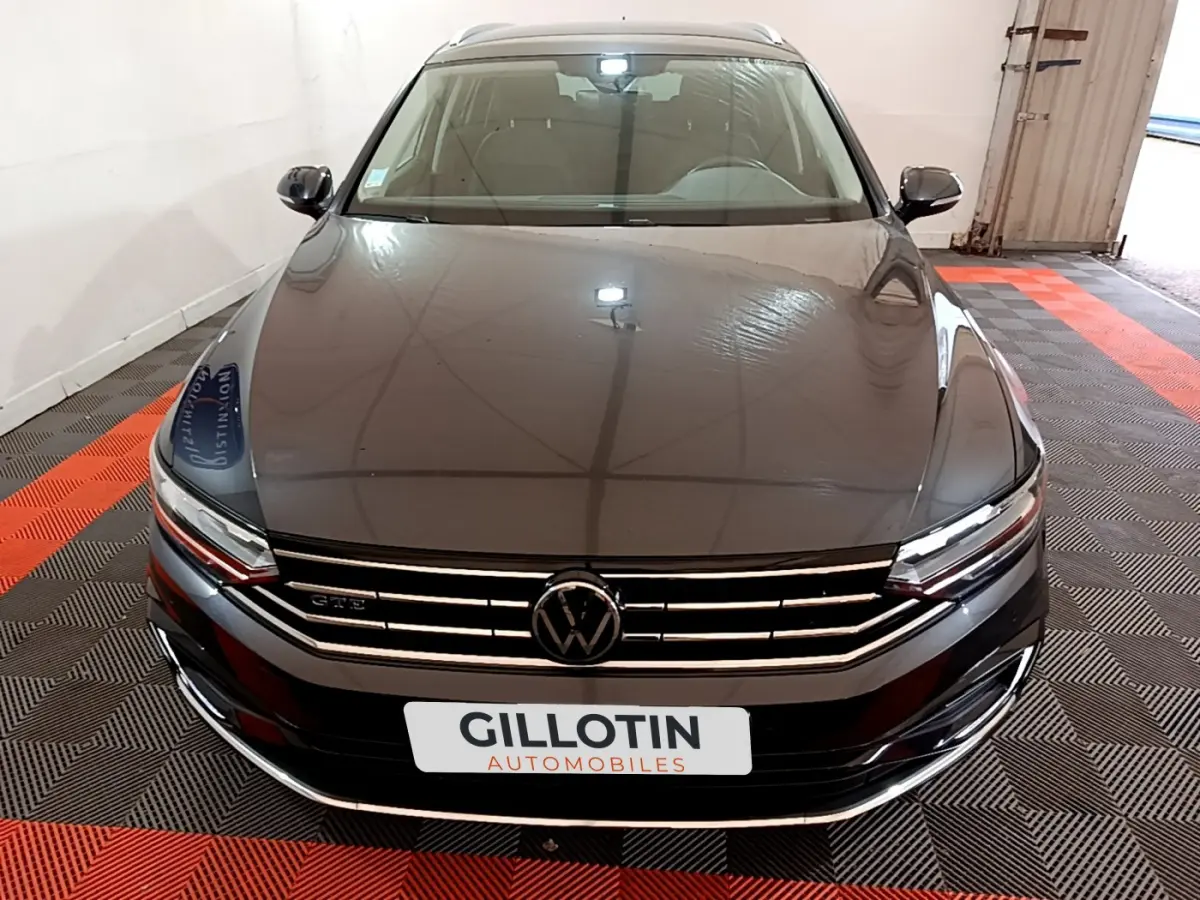 Vue avant d'une Volkswagen Passat GTE gris foncé stationnée sur sol à damier noir et rouge, avec calandre chromée.