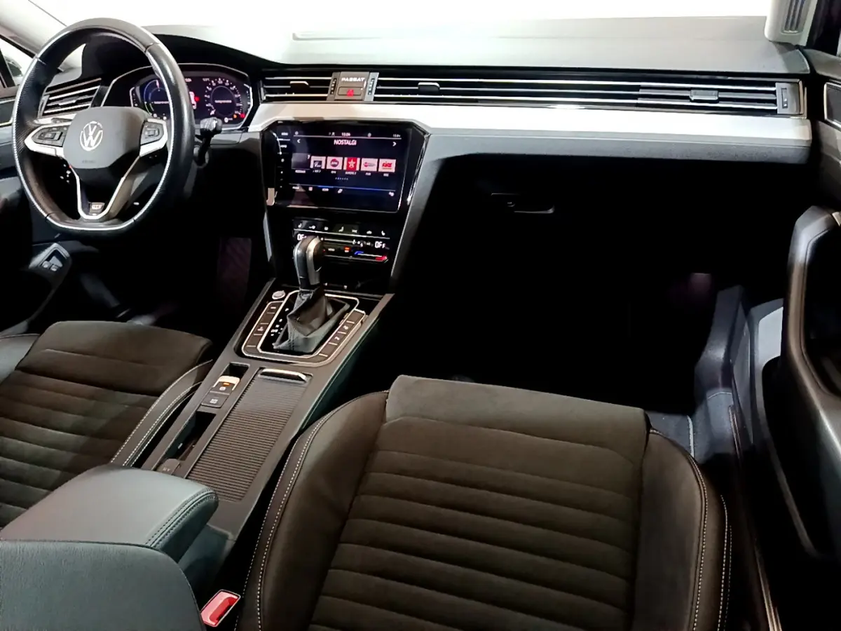 Intérieur avant de la Volkswagen Passat hybride rechargeable 2022, tableau de bord moderne avec écran tactile et volant cuir noir.