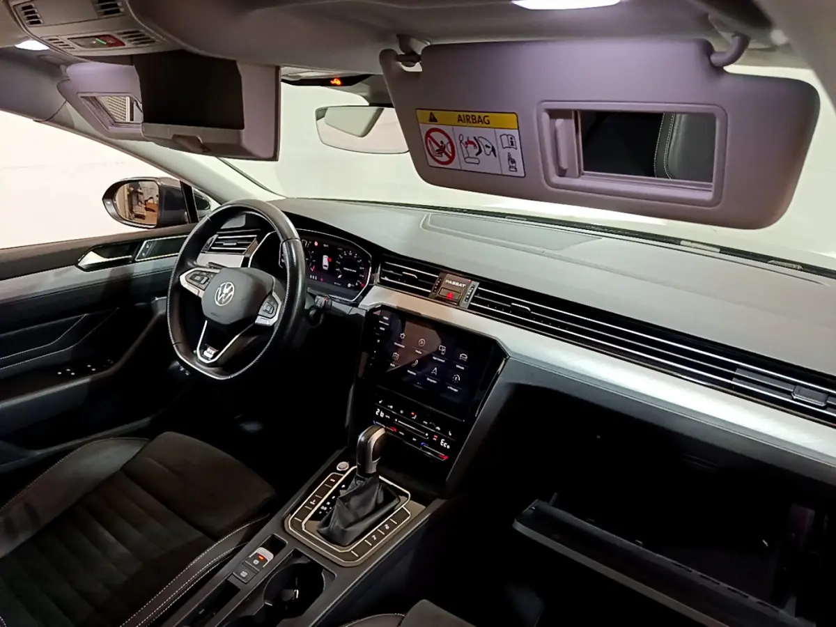 Intérieur avant de la Volkswagen Passat hybride rechargeable 2022, tableau de bord moderne avec écran tactile et volant cuir noir.