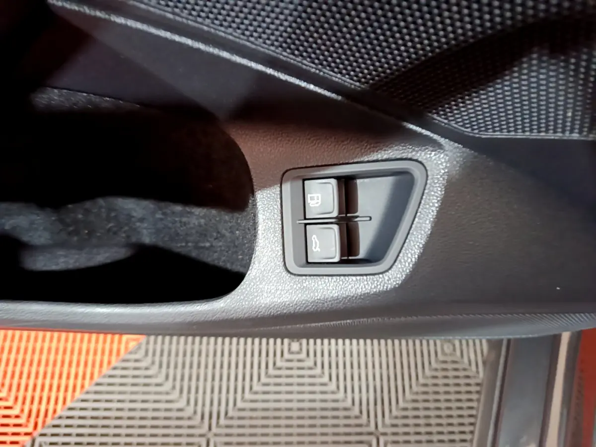 Gros plan sur les boutons d'ouverture du coffre et du réservoir dans la porte côté conducteur de la Volkswagen Passat gris foncé.