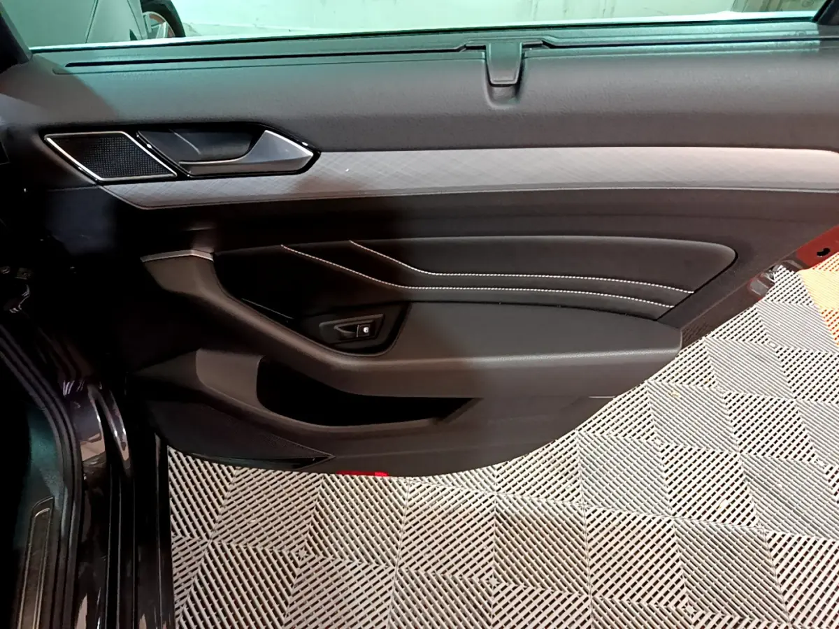 Porte intérieure côté gauche de la Volkswagen Passat GTE 2022 gris foncé, avec surpiqûres blanches et insert décoratif.