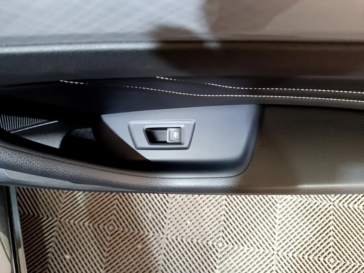 Détail de la poignée intérieure de porte côté gauche en plastique noir avec surpiqûres blanches sur la garniture, Volkswagen Passat GTE 2022.