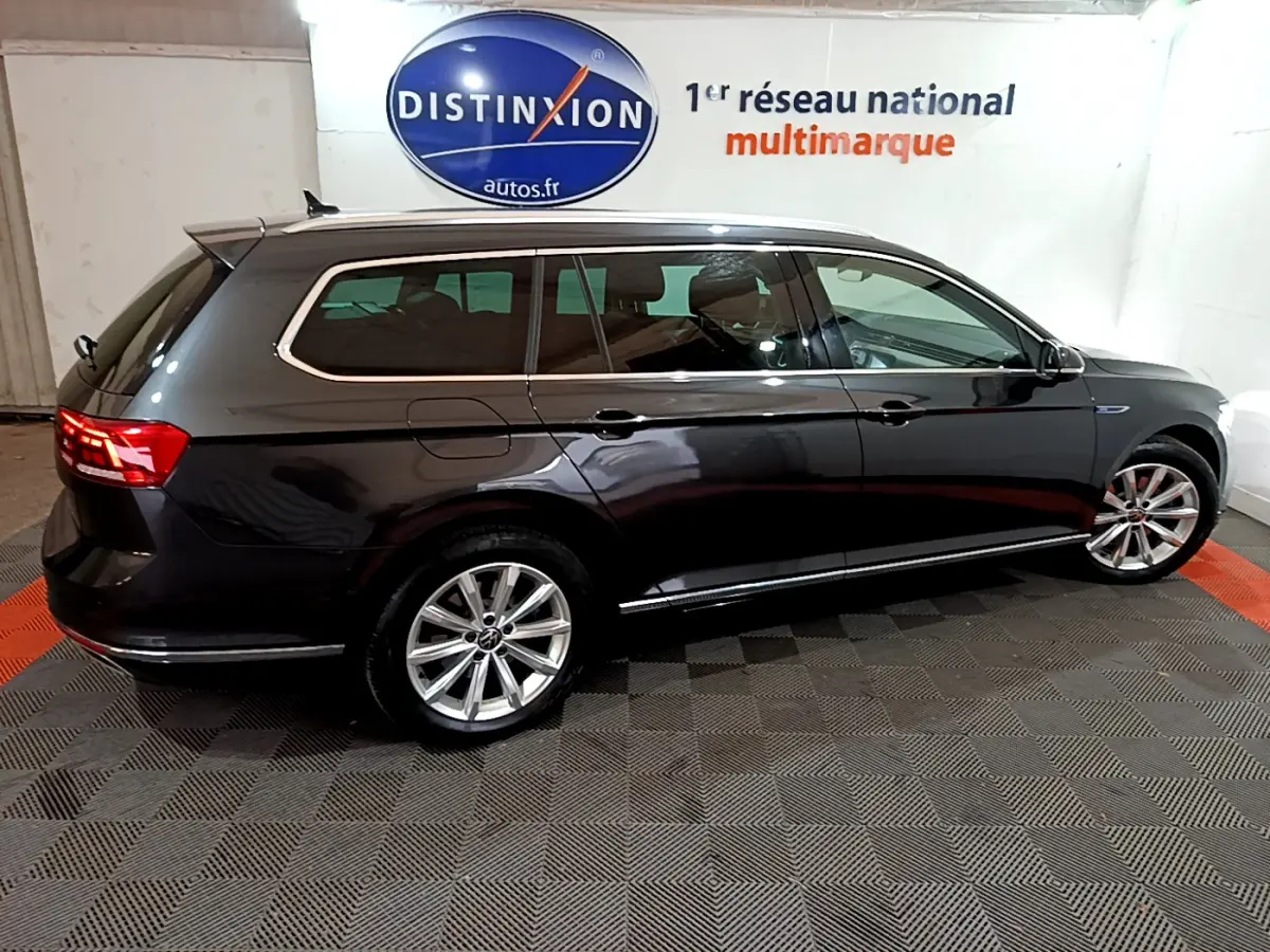 Volkswagen Passat SW hybride rechargeable gris foncé vue de profil côté gauche dans un showroom intérieur.