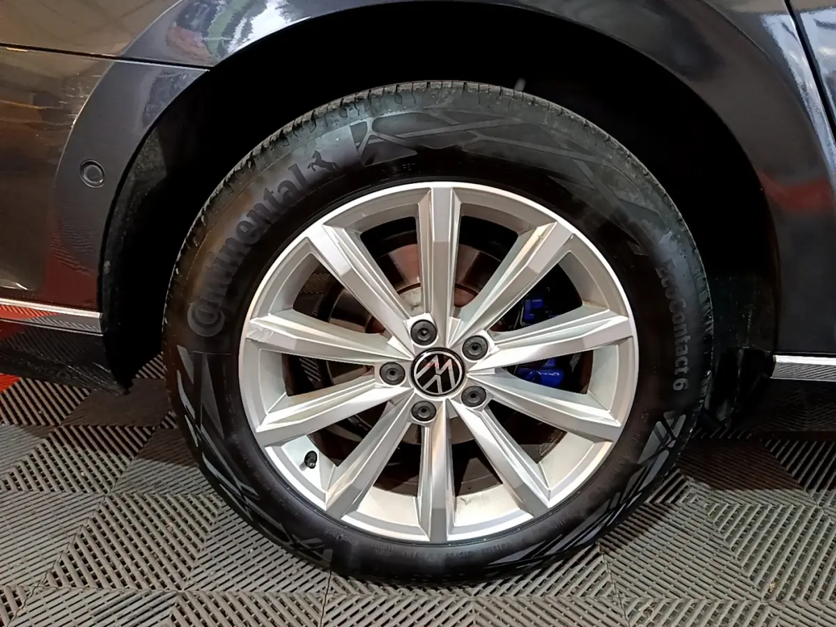 Gros plan sur la roue avant droite gris foncé d'une Volkswagen Passat hybride rechargeable avec jante alliage et étrier de frein bleu.