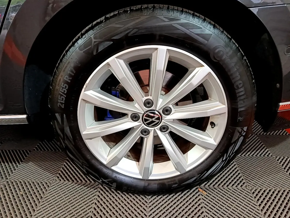Gros plan sur la roue avant droite d'une Volkswagen Passat GTE gris foncé, jante alliage à 10 branches et frein bleu visible.
