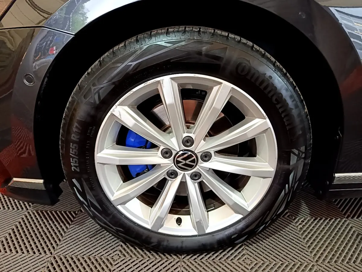 Gros plan sur la roue avant gauche gris foncé d'une Volkswagen Passat GTE avec étrier de frein bleu visible.