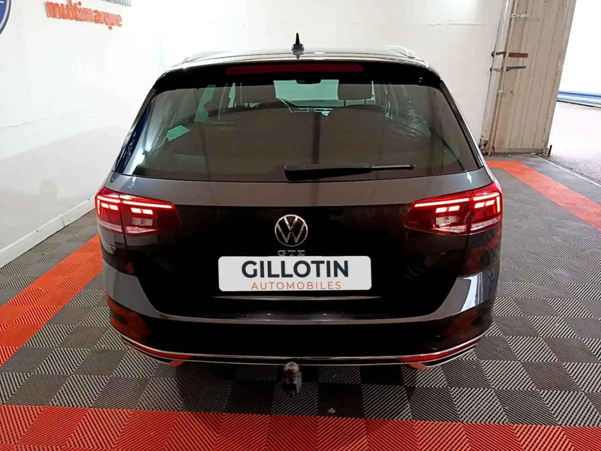 Vue arrière d'une Volkswagen Passat SW GTE hybride rechargeable gris foncé avec feux LED allumés et attelage visible.
