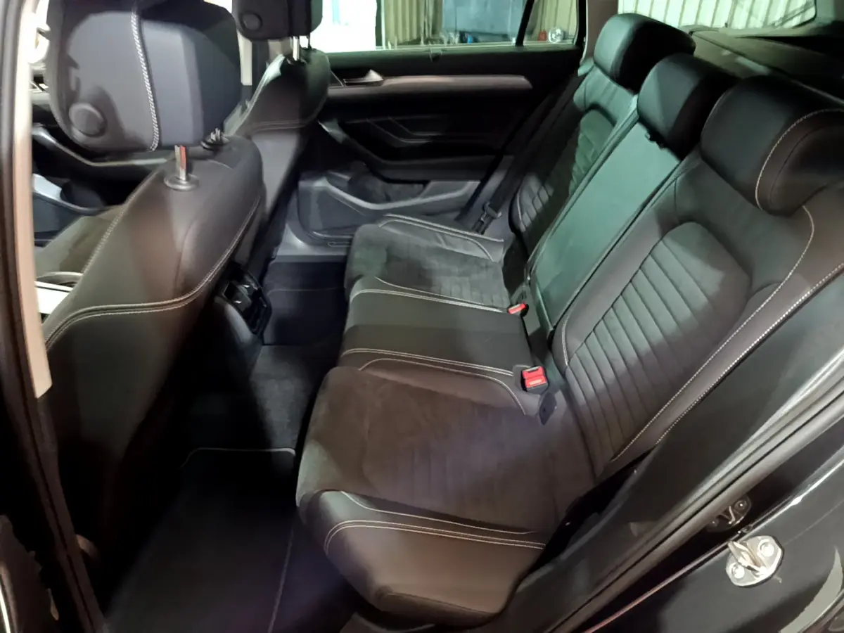 Vue intérieure côté droit sur la banquette arrière en cuir noir avec surpiqûres blanches de la Volkswagen Passat SW GTE hybride rechargeable 2022.