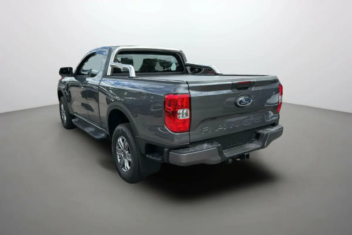 Ford Ranger gris carbone 2025 en vue 3/4 arrière droit avec benne et barres de protection chromées.