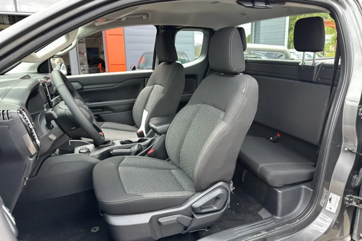 Intérieur du Ford Ranger 2025 gris carbone, vue côté gauche montrant sièges avant et banquette arrière compacte Supercab.