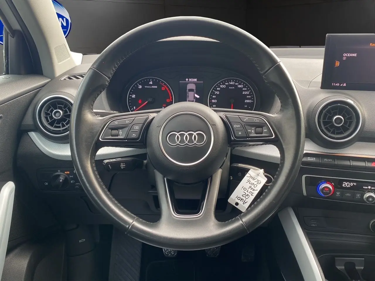 Vue rapprochée du volant noir d'un Audi Q2 30 TDI 2019 avec tableau de bord et écran central affichant la température.