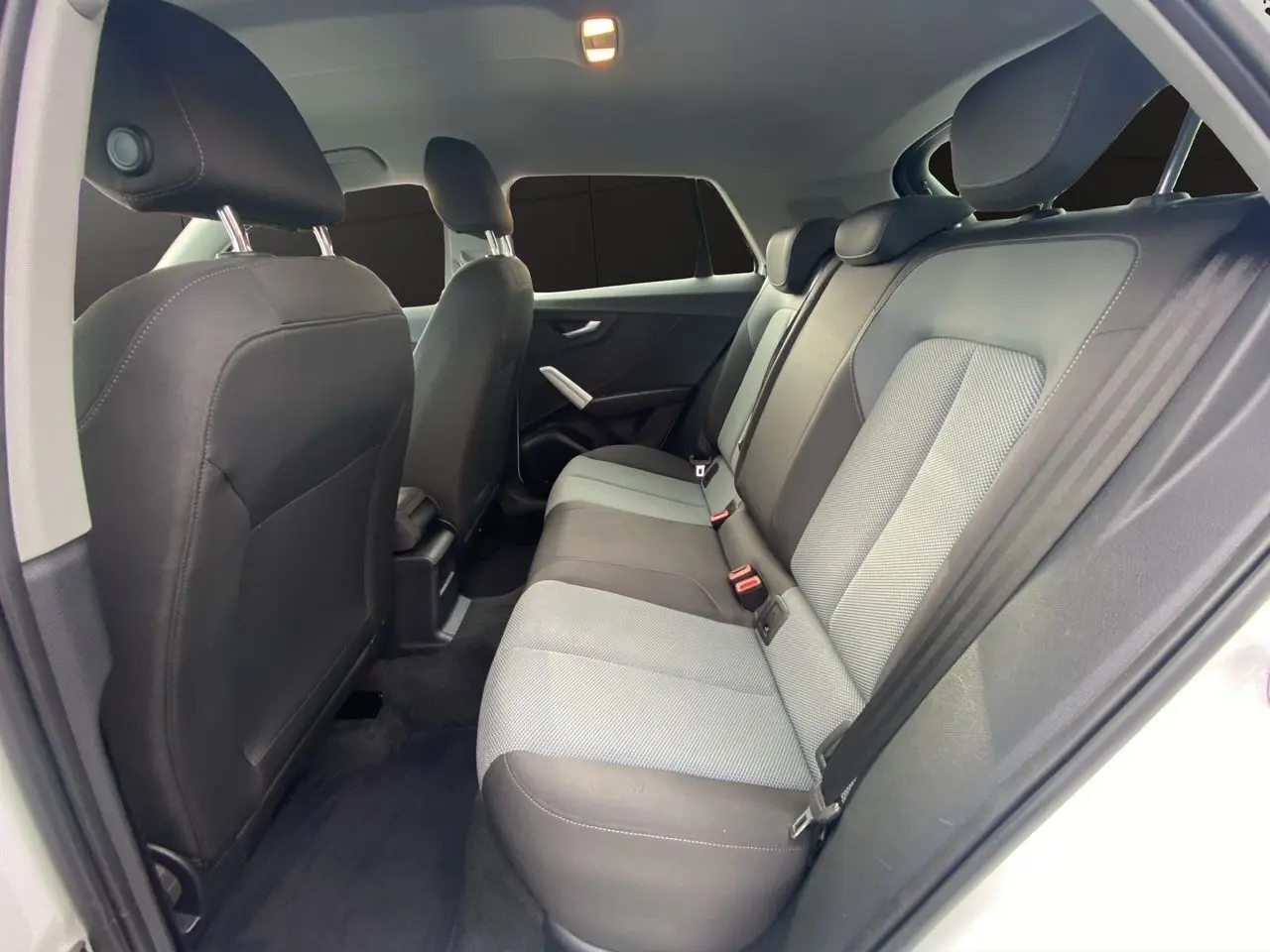 Vue intérieure arrière droite de l'Audi Q2 2019, sièges tissu bicolores gris et noir avec ceintures de sécurité.