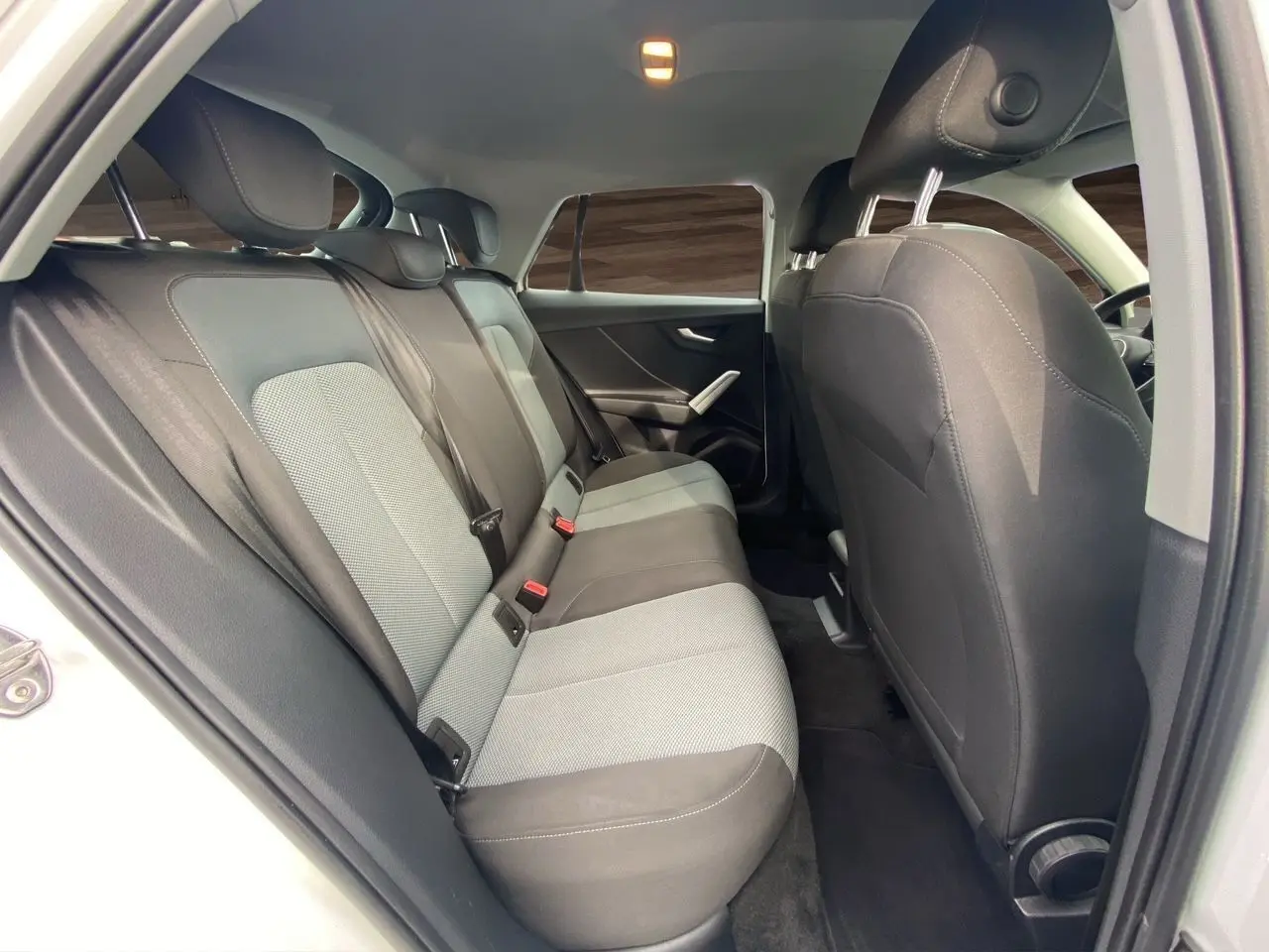 Vue intérieure arrière côté gauche de l'Audi Q2 30 TDI 116 BVM6 2019, avec sièges tissu noir et gris.