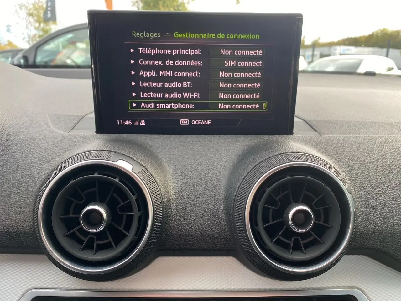 Détail du tableau de bord noir de l'Audi Q2 blanc 2019 avec écran central affichant les connexions non connectées.