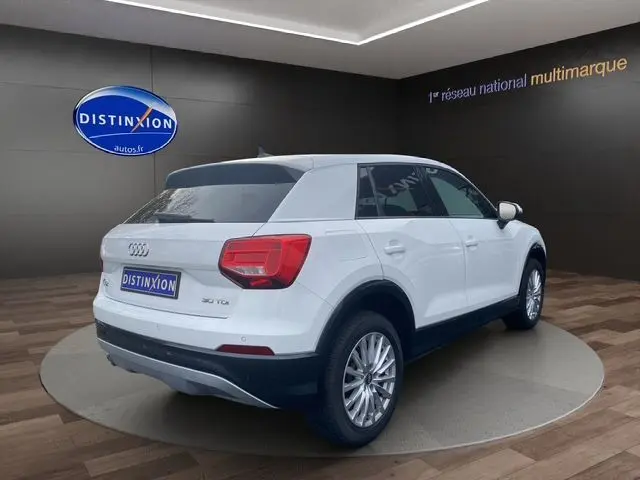 Audi Q2 blanc vue 3/4 arrière droit, SUV compact avec jantes alliage et feux arrière LED distinctifs.