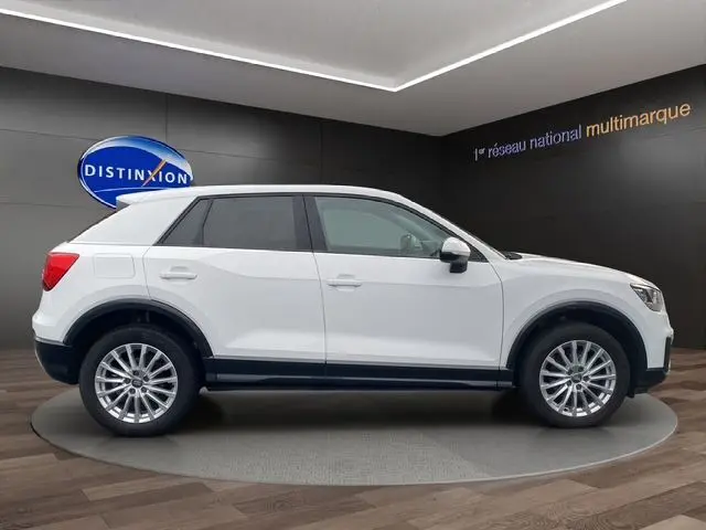 Profil droit d'un Audi Q2 blanc 2019, SUV compact avec jantes alliage et toit contrasté noir en showroom.