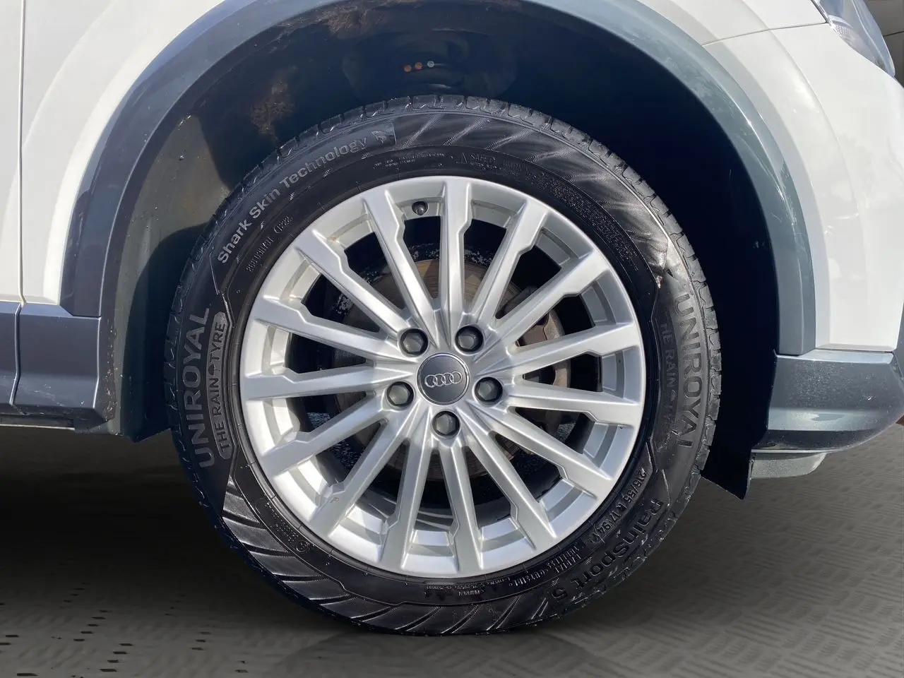 Gros plan sur la roue avant gauche blanche d'un Audi Q2 30 TDI 116 BVM6 avec jante argentée multi-branches.