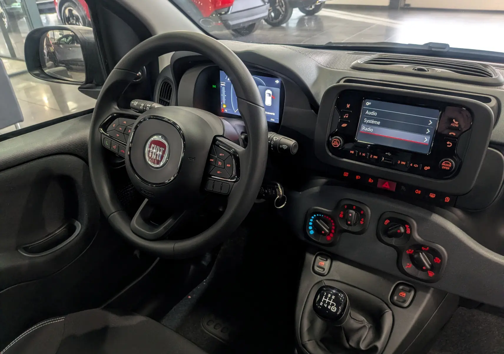 Vue intérieure côté conducteur de la Fiat Panda 1.0 Hybrid 2025 avec tableau de bord numérique et écran tactile radio.