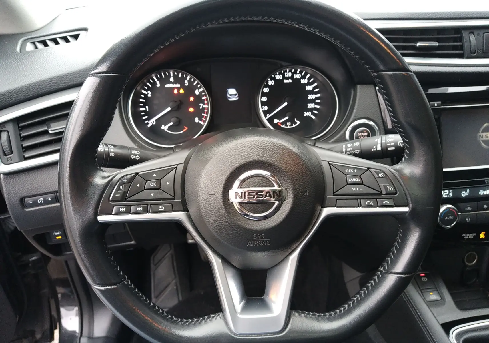 Vue rapprochée du volant cuir noir du Nissan Qashqai 2019, avec commandes intégrées et tableau de bord visible.