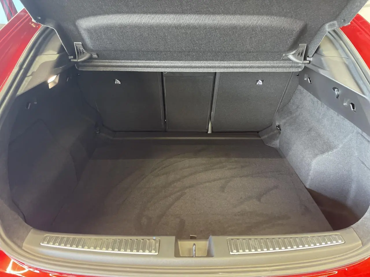 Coffre ouvert vu de l'arrière d'une Renault Rafale 2025 rouge avec intérieur de coffre noir et tapis plat.