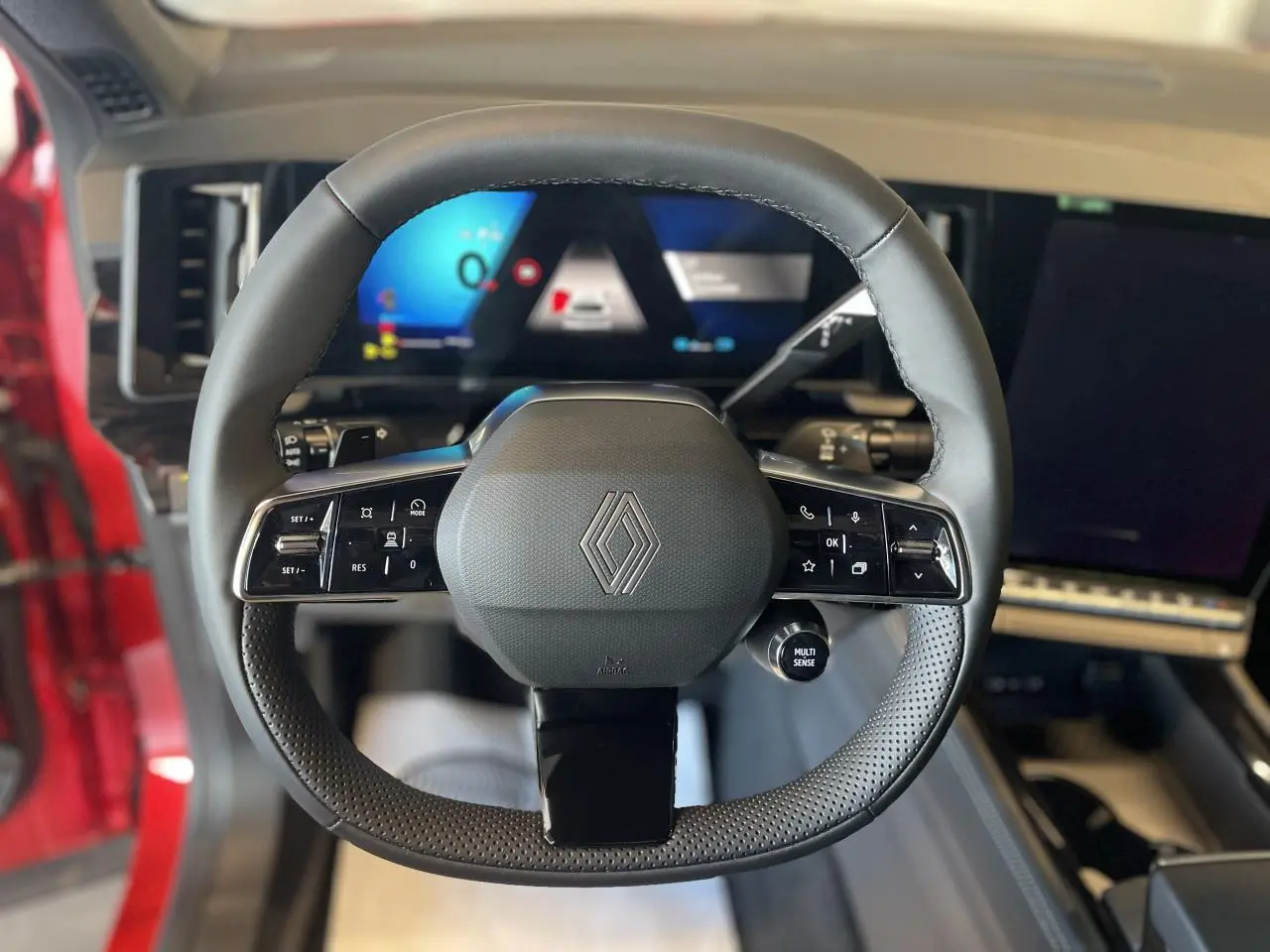 Vue frontale du volant Renault Rafale hybride 2025 avec commandes intégrées et tableau de bord numérique lumineux.