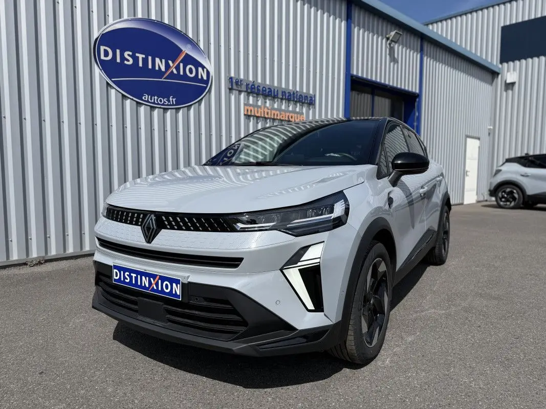 Renault Captur 2025 gris rafale avec toit noir, vu en 3/4 avant droit devant un bâtiment industriel.
