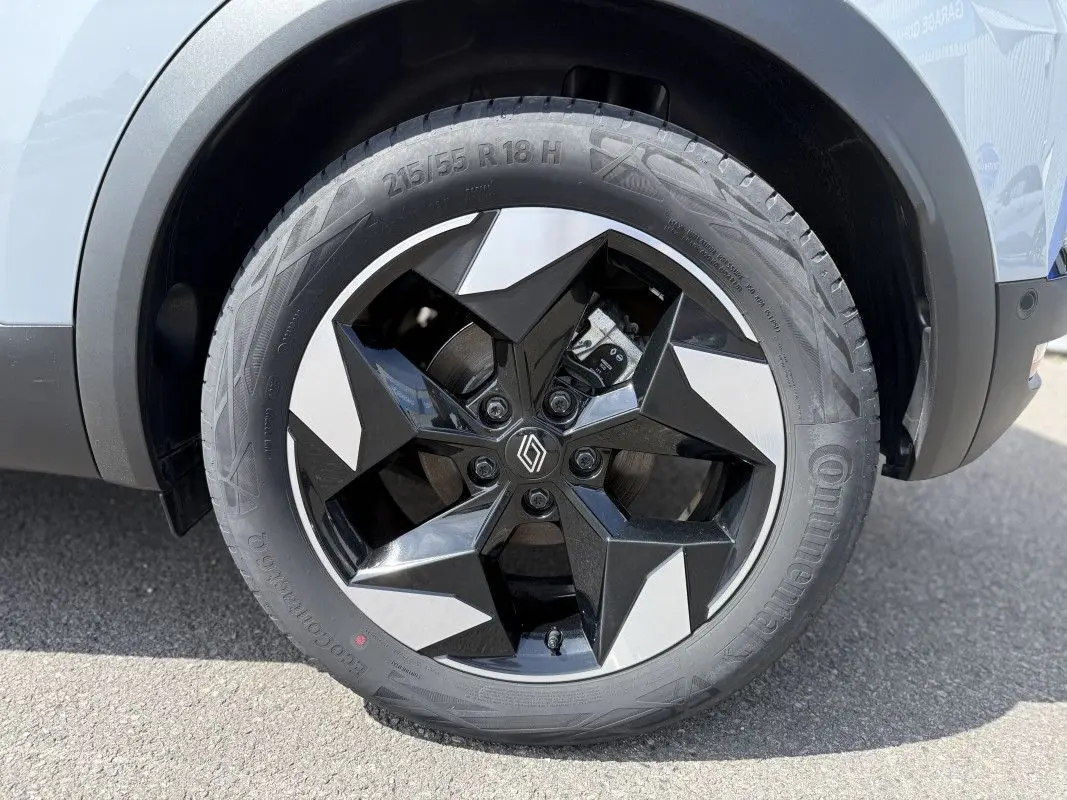 Gros plan sur la roue avant droite du Renault Captur gris Rafale avec jante noire et argentée au design étoilé.