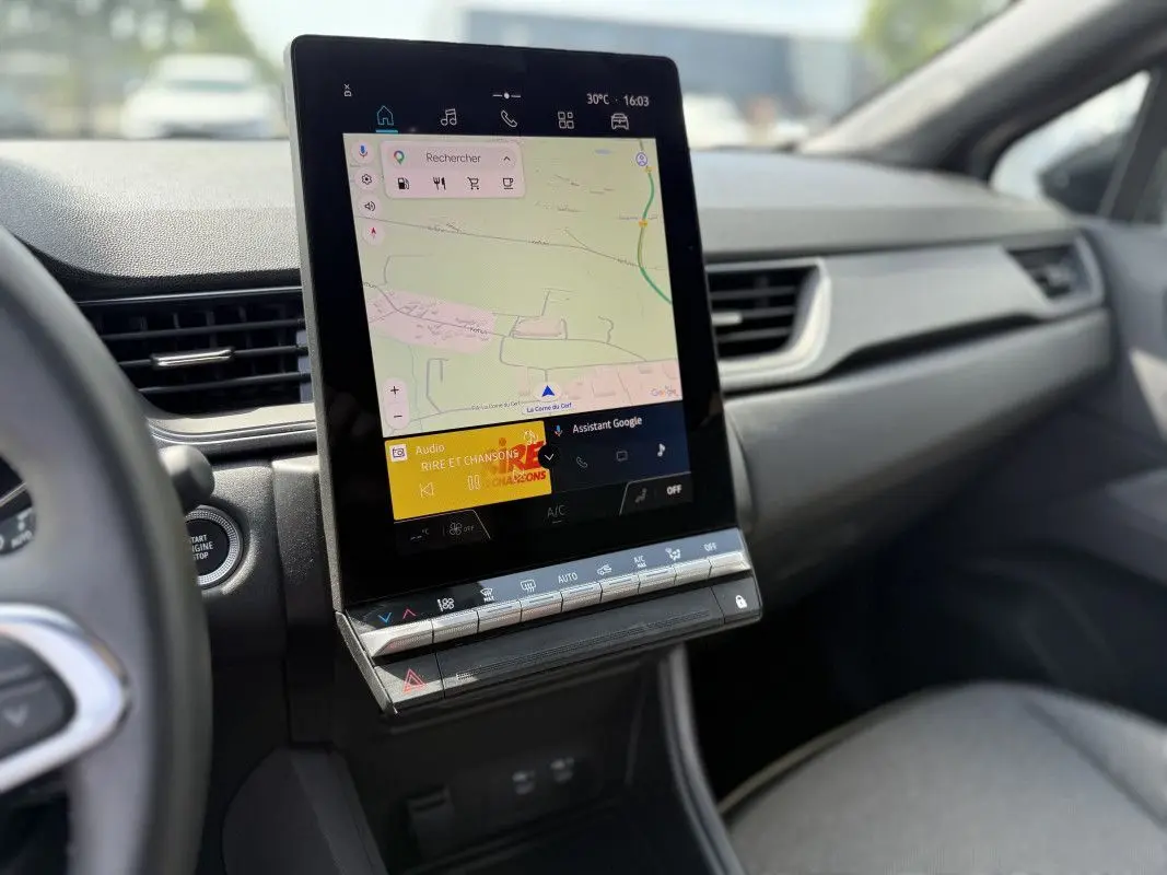 Vue intérieure du tableau de bord du Renault Captur 2025, écran tactile central affichant la navigation et commandes climatisation.