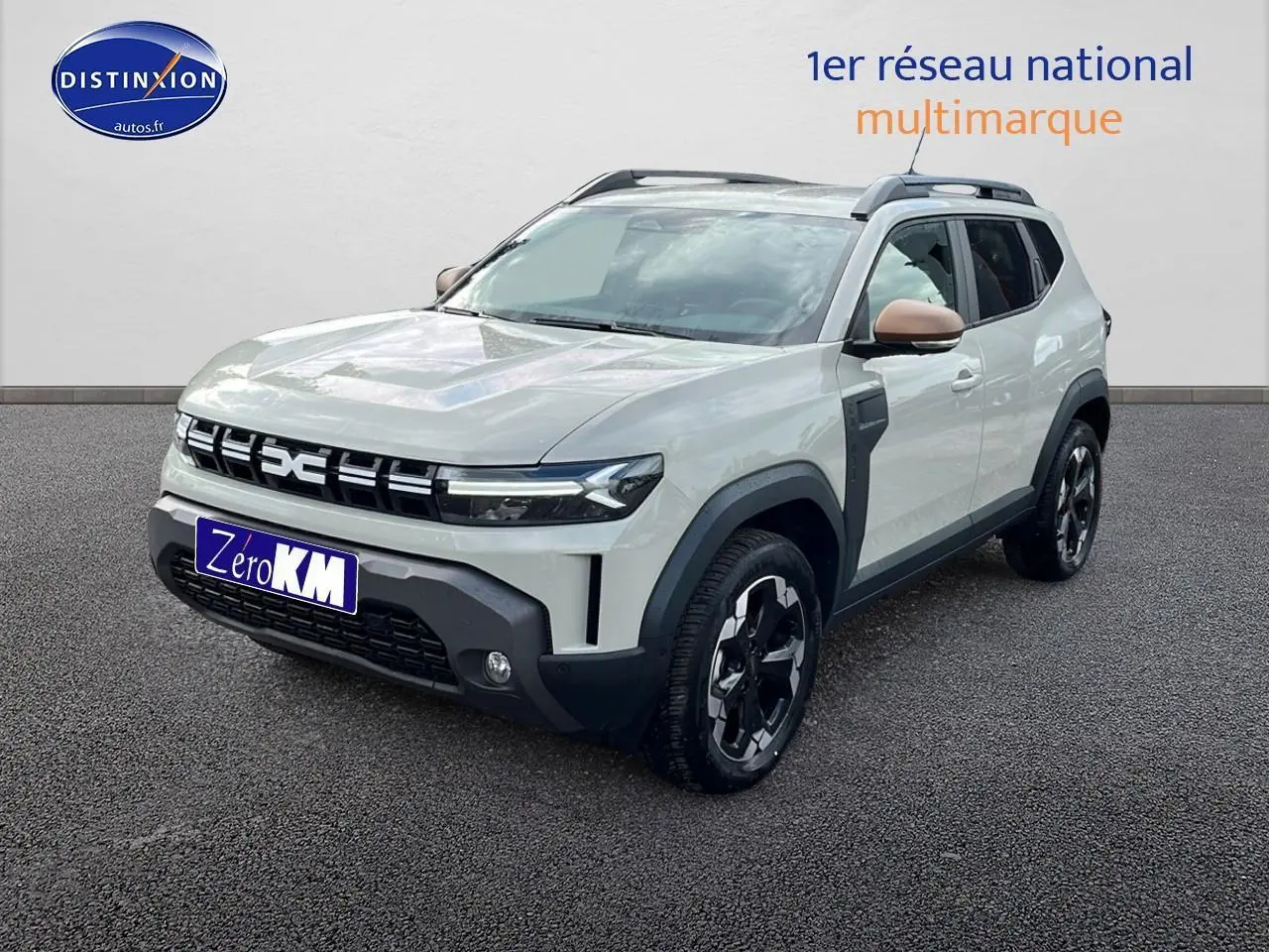 Vue 3/4 avant d'un Dacia Duster 2025 Sandstone avec rétroviseurs couleur sable et barres de toit noires.