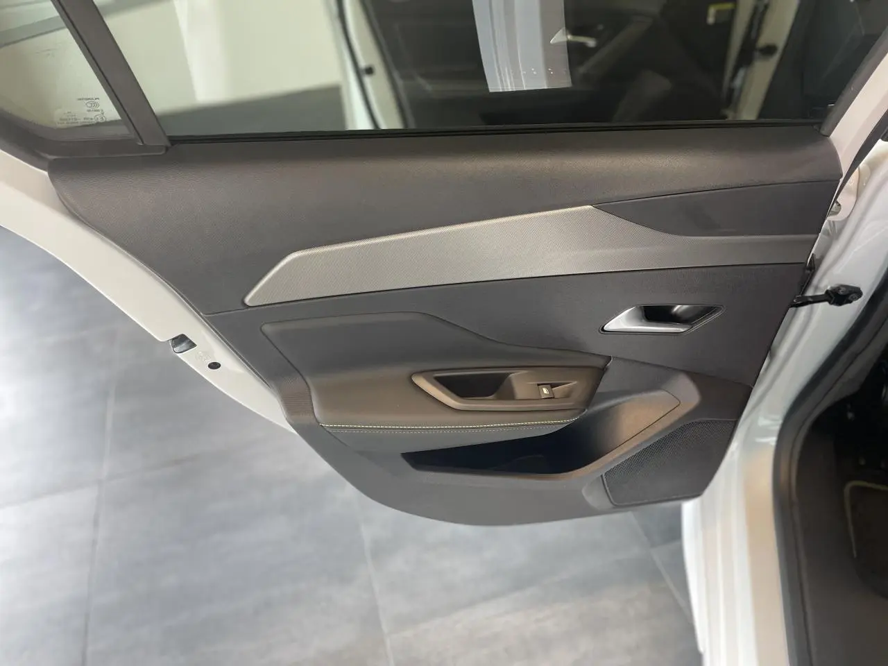 Porte arrière côté droit ouverte d'une Peugeot 308 blanche, avec panneau intérieur noir et insert décoratif gris.