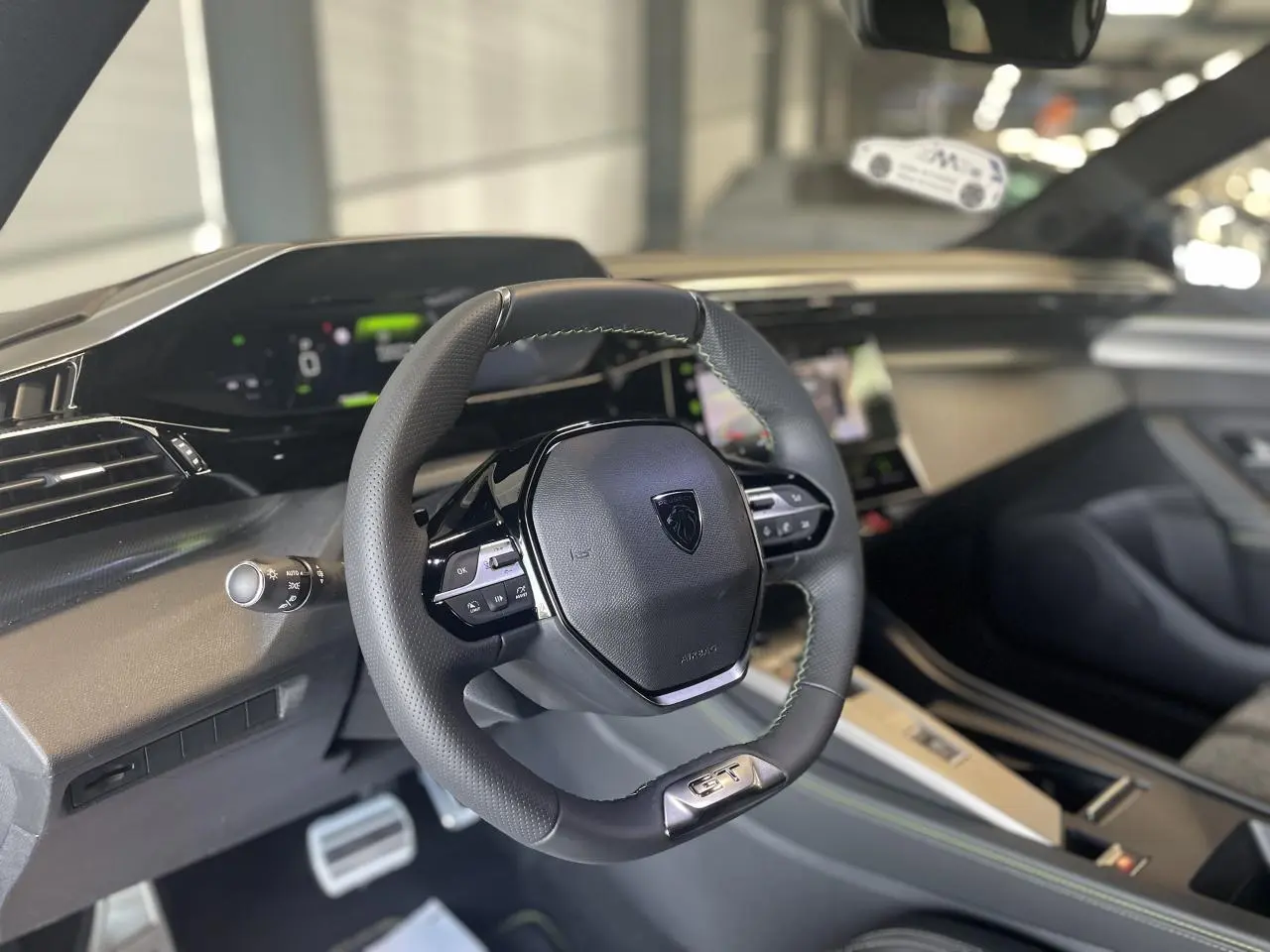 Vue intérieure du volant cuir Peugeot 308 GT 2025 avec combiné numérique et finitions noires et aluminium.