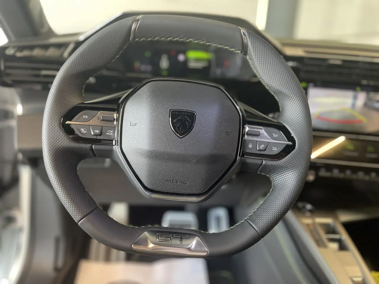 Volant cuir Peugeot 308 GT vu de face avec logo lion et commandes intégrées, intérieur moderne en arrière-plan flou.