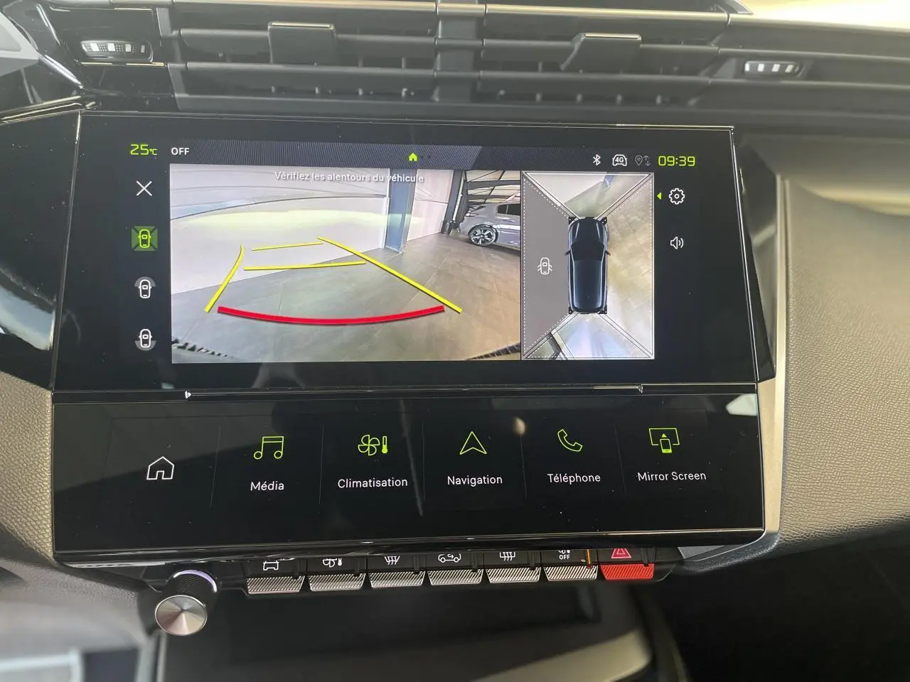 Vue rapprochée de l'écran tactile central de la Peugeot 308 blanche affichant la caméra de recul et la navigation.